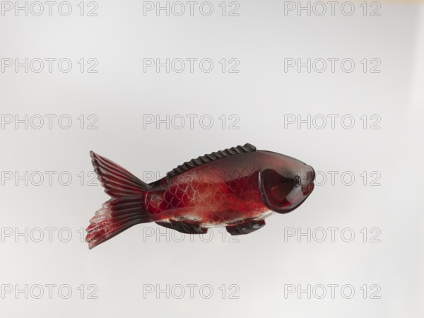 Snuffbox, carved with carp fish, Chinese, Qing dynasty 1644–1911, glass stained purple with gold chloride, 18th century, China, vessel; height 11.0 cm, width 4.0 cm., A carved fish-shaped object made of translucent material with deep red and darker maroon tones, showing carved scales, fins, and a ridged dorsal edge; the tail fin has striated grooves and the body displays varying shades of red and darker highlights against a pale neutral background.