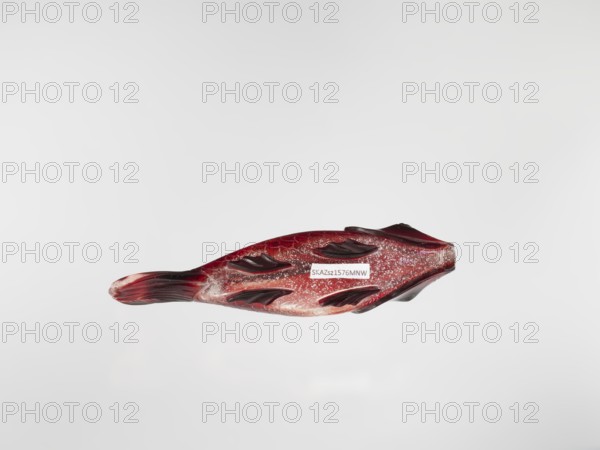 Snuffbox, carved with carps fish, Chinese, Qing dynasty 1644–1911, glass stained purple with gold chloride, 18th century, China; vessel; height 11.0 cm, width 4.0 cm., A glossy object shaped like a fish with a streamlined body and a tapered tail sits against a light gray background; the object is predominantly deep red with darker maroon accents along raised fin-like ridges and tail, and it has areas of pale pinkish and translucent coloring with scattered sparkly flecks that appear silvery or white.