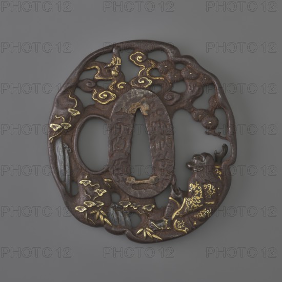 Crossguard tsuba, Sôten school, Kitagawa Sôten attributed, pines, bamboos, plants, waterfall, Uba under a pine tree by a stream looking at the sky where the moon emerges from behind clouds; positive openwork pattern, inlaid with gold and shakudo; oval tatemaru gata with irregular, rounded edge; signed. 1701–1730 Edo period, 1603–1868. Japan; Ômi Eshu province. Tsuba. Height 7.1 cm; width 6.7 cm., A round, openwork metal object with a dark brown surface and a few areas of gold detailing, shaped with an irregular outer rim and two central oval openings; the design shows a group of cloud-like swirls near the top highlighted in gold, a reclining animal-like figure on the right with gold decorative markings on its body, a few leafy plant forms and bamboo-like elements toward the lower left rendered in gold accents, and textured, slightly raised surfaces throughout creating a carved, sculptural appearance against a gray background.