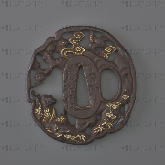 Crossguard tsuba, Sôten, / school, Kitagawa, Sôten, / personal slogans / author, pines, katana, Uba, sword crossguards, Japanese art, Japanese culture, bamboos, plants, waterfalls, swords, weapons, edged weapons, Edo 1603-1868, Tsuba oval tatemaru gata with an irregular, rounded edge, decorated with a positive openwork pattern, inlaid with gold and shakudô, depicting Uba under a pine tree by a stream looking at the sky in which the moon emerges from behind the clouds. Signed. 1701–1730 Edo Period, Japan; Ômi Eshu province. Tsuba; height 7.1 cm, width 6.7 cm., A circular metal ornamental object with an openwork design showing a stylized natural scene, primarily dark brown with areas of gold inlay and small highlights of grey and black; the outer rim is irregular and organic, enclosing carved tree-like forms, cloud or smoke-like swirls, and leafy plant motifs; a reclining animal figure appears near the lower left, decorated with gold patterns, and a group of small leaves and bamboo-like ...