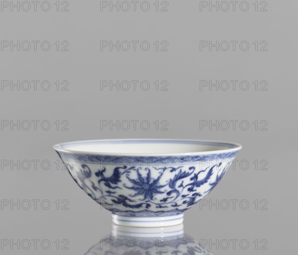 Bowl, bowl with a slightly flared rim, blue and white porcelain, ceramics, lotus and lotus tendril ornament, Qianlong style, Qing dynasty 1736–1795, China, Chinese, vessel, height 4.3 cm, diameter 9.8 cm, purchase provenance., A shallow porcelain bowl with a flared rim and a narrow foot, decorated with a repeating floral and vine pattern in blue on a white background, sitting on a reflective surface against a gray backdrop, showing a few fine decorative bands near the rim and foot and several curving floral motifs around the body in shades of blue and white.