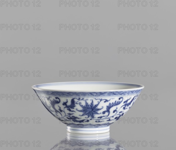 Bowl, lotuses, ceramics, blue-and-white porcelain, Chinese art, Qianlong style, Qing style, lotus tendril ornament, Chinese, Qing 1644–1911, bowl with a slightly flared rim, 1736–1795, China, vessel; height 4.3 cm, diameter 9.8 cm, A porcelain bowl with blue decorative floral and scrolling patterns on a white background, showing a band of blue ornamentation near the rim and a repeating floral motif around the body, sitting on a short foot with blue rings, reflected on a glossy surface; visible colors include white, blue, gray, and a soft neutral background.