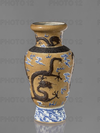 Vase, Chinese, 19th century. Steam vase; ovoid; short, slightly flared foot; pear-shaped belly; neck bulging at the rim. Ceramic vessel with cracklework decoration, dragons, clouds, flames, and geometric ornaments. Height 43.6 cm; diameter 15 cm. Repossession, A tall ceramic vase with a narrow neck and flared rim sits against a gray background; the vase has a crackled tan surface with raised dark brown dragon motifs wrapping around its body and neck, and a band of textured dark brown near the shoulder, while blue and white cloud-like decorative elements are scattered across the tan areas and a blue and white patterned base supports the vase.