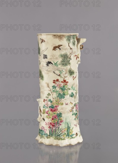 Vase, Tôritei; satsuma; Japanese; decorated with insects, tree trunks, flowers, plant ornaments, birds, peonies, pines, crickets, monkeys, kacho flowers and birds, kachôga iconography, lotuses, irises, grasses, cranes; Meiji period 1868–1912, ca. 1885 Meiji 18; Japan, Kyoto, Awata; vessel; height 32 cm, width 15 cm., A tall cylindrical ceramic vase with an uneven rim and textured surface, decorated with painted natural scenes; the body shows a group of birds in flight and perched among pine-like branches, and a dense cluster of flowering plants and grasses at the lower portion, including blossoms and leafy stems. The painted colors visible include cream as the base color, greens for foliage, reds and pinks for flowers, yellow and purple accents in blossoms, brown and tan tones in branches and some birds, white on some bird plumage, and small touches of black for detailing. The vase has a slightly irregular, handmade appearance with a few raised protrusions on the sides and a scalloped ...