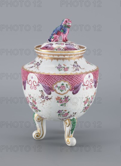 Vase with a Lid, Samson, Edmé 1810–1891, porcelain, Chinese style, 19th century, France. Lid topped with a modeled lion figure. European-style decoration with plant motifs, stylized fo lion iconography, and coats of arms. Vessel height 29.8 cm, diameter 18.5 cm. Repossession provenance and Silesia noted., An ornate ceramic covered vessel on three curled legs with a small sculpted animal finial on the lid; the vessel is primarily white with extensive decorative painting in pink, purple, green, gold, and touches of blue, featuring floral motifs, scalloped medallion shapes, lattice-like pink banding, and gilded accents; the lid has matching floral decoration and the finial is painted pink with blue mane details and green highlights; the three legs are white with gold scrollwork and green leaf-like ornamentation; the surface shows embossed patterns and delicate painted sprays of flowers in pink, purple, and green against the white ground.