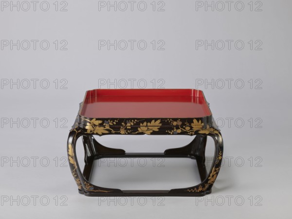 Tray on legs kakeban, gift; Japanese, Edo period early 19th century. One of a set of three tables placed one on top of the other; almost square red tops with high edges and bow legs connected at the bottom by a square frame forming the base. Sides and legs covered with black lacquer and sprinkled with gold using the maki-e technique with flowering cherry, plum, pine branches, twigs — winter motifs. Piece of furniture. Height 25.3 cm; width 47.5 cm; depth 46.0 cm., A low, square tray table with a glossy red top set within a black frame, the frame and curved legs decorated with gold floral motifs and small accents of gray; the table sits on a neutral pale gray surface against a light gray background.