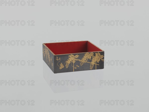 Portable picnic set sagejûbako, Rectangular cabinet without side walls on a stand with two stacked food containers set incomplete; originally four; beside them on the stand are two tin sake bottles. Top tabletop has a handle, one small drawer, and a shelf for trays missing. Entire exterior covered with black roiro-nuri lacquer; interiors of food containers with vermilion lacquer. Surface ornament executed in hiramaki-e and nashiji techniques, depicting blooming wisteria, camellias, plum trees, wolfberries, mon rosettes/coins, and leaves. Such portable eating sets were variously called in Japan kuchi?, sagej?, hanami bent? and were popular from the Momoyama period mid-16th–early 17th c. and in the 18th–19th centuries. 19th century Edo–Meiji periods, Japan. Dimensions: height 31.3 cm; width 30.5 cm; depth 17.8 cm; weight 2.29 kg., A rectangular open box with a red interior and a black exterior decorated with gold floral patterns sits on a reflective pale surface, showing a faint mirrored...