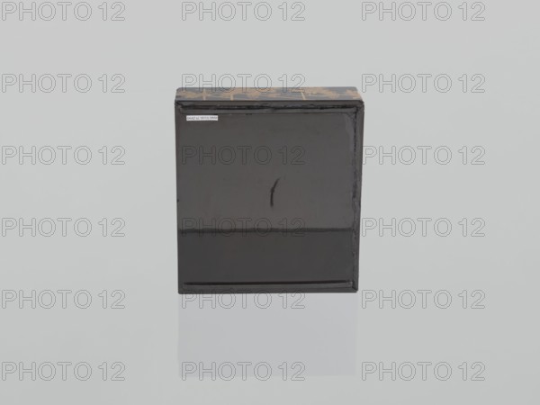 Portable picnic set sagejûbako, Rectangular cabinet without side walls. On a stand are two food containers stacked set incomplete; originally four; next to the containers on the stand are two tin sake bottles. The top tabletop, with a handle, has one small drawer and a shelf for trays missing. Entire surface covered with black roiro-nuri lacquer; interiors of the food containers are vermilion lacquer. Ornament executed in hiramaki-e and nashiji techniques depicting blooming wisteria, camellias, rosettes coins, leaves, plum trees, and wolfberries; includes a mon. Such portable eating sets were called in Japan kôchô, sagejû, hanami bentô and were popular from the Momoyama period mid-16th–early 17th c. and in the 18th–19th centuries. 19th century Edo–Meiji period, Japan. Item measurements: height 31.3 cm, width 30.5 cm, depth 17.8 cm, weight 2.29 kg., A rectangular box with a glossy black front and sides sits centered on a pale gray background, showing a faint vertical scratch on the fron...