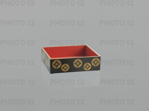 Portable picnic set sagejûbako, Rectangular cabinet without side walls. On a stand are two food containers stacked set incomplete; originally four; next to them on the stand are two tin sake bottles. The top tabletop, with a handle, has one small drawer and a shelf for trays missing. Entire surface covered with black roiro-nuri lacquer; interiors of food containers in vermilion lacquer. Ornament made using hiramaki-e and nashiji techniques showing motifs of blooming wisteria, camellias, and rosettes coins. Such portable eating sets were variously called in Japan kocho, sageju, hanami bento and were popular from the Momoyama period mid-16th–early 17th century and in the 18th and 19th centuries. 19th century Edo–Meiji periods, Japan. Materials: lacquer, tin; height 31.3 cm, width 30.5 cm, depth 17.8 cm, weight 2.29 kg., A shallow rectangular box with an open top, showing a red interior and thin light-colored edges, has black exterior sides decorated with a repeating gold circular motif; ...