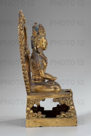 Amitayus, Himalayan art, Chinese art, Tibetan Buddhist art, Himalayan culture, Chinese culture, Sino-Tibetan style, Qing 1644–1911, Buddha iconography, ushnisha, inscriptions, crowns, lotus throne iconography, halos. Amitayus, the Buddha of Infinite Life, shown seated in a meditative pose with hands folded in a meditative gesture. Hair styled in a chignon with a high bun tied on top of the head; hair is covered in blue. Head adorned with a five-leaf crown inlaid with semi-precious stones, set on a headband mounted on the underside. Back painted orange. The hair flowing to the shoulders, the sash covering the shoulders, the stones, and the earrings probably large, flower-shaped, falling on the shoulders are missing. Bottom of the sculpture closed with a wooden plaque secured with metal pins and mortar; the plaque bears a drawing of a quadruple vajra. Date: 1770. Place of origin: China. Sculpture. Height 22.0 cm; width 11.5 cm; depth 8.9 cm., A gilded seated figure on an ornate throne vi...