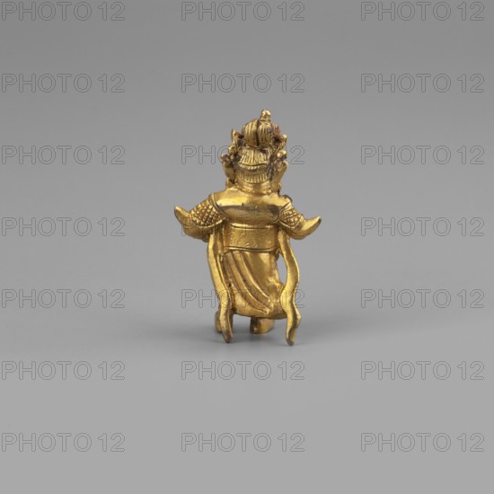 Vaisravana Tib. Namtose, Tib. rnam thos sras, sometimes identified with the yellow Jambhala, an emanation of Buddha Ratnasambhava — guardian of the north. Sculpture figurine, cult object, height 3.4 cm. Himalayan/Tibetan Buddhist art; 2nd half of the 18th–19th century. Maker, provenance: purchase. Possible origin: Tibet or Mongolia., A small gold-colored metal figurine viewed from the back standing against a plain light gray background, showing a figure with an ornate headdress, textured shoulder armor, flowing drapery down the back, and raised arms with curved sleeve-like extensions; the colors visible are gold on the figurine and shades of light gray in the background and surface.