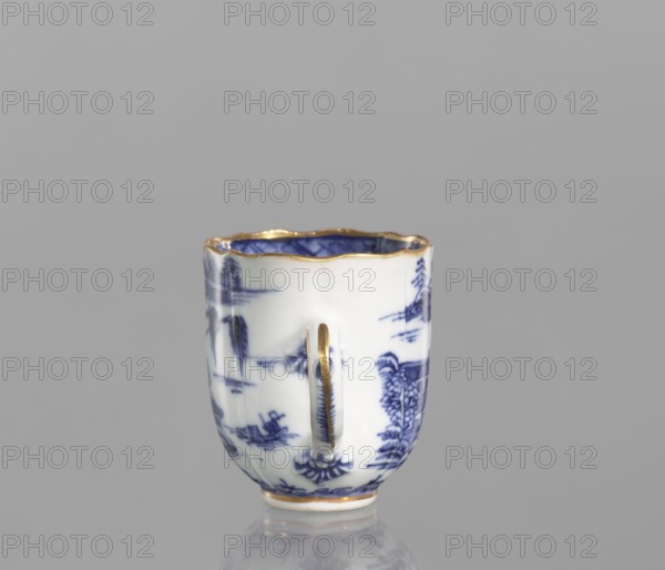 Cup;, Porcelain, blue-and-white; Chinese, Qing dynasty, 19th century. Landscape motifs. Part of a 22-piece tea and coffee service teapot, 6 cups, 6 saucers, a bowl, a cover, and a plate. Vessel. Height 6.5 cm; width/diameter 5.9 cm., A small porcelain cup with a scalloped rim and a single vertical handle sits on a reflective surface against a plain gray background; the cup is primarily white with blue painted landscape motifs and has gold trim along the rim, the handle, and the base, with the interior showing blue decoration and gold edging.