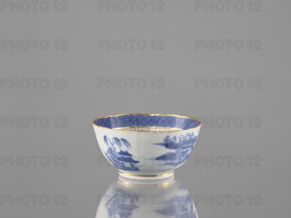Teapot, ceramics, blue-and-white porcelain, Chinese, Qing dynasty, 19th century Qing, 1644–1912. Landscape motifs. Part of a 22-piece tea and coffee service teapot, 6 cups, 6 goblets, 6 saucers, a bowl, a cover, and a plate. Vessel; height 7 cm, diameter 14.3 cm., A small porcelain bowl sits centered against a plain gray background, showing a white exterior decorated with blue landscape scenes and a blue interior patterned band; the rim and a few narrow bands on the foot have a gold trim, and the bowl is reflected faintly on the glossy surface beneath it.