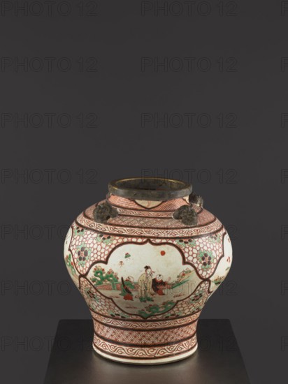Vase, Colored porcelain vessel, Qing dynasty mid-18th century, China. Mascarons on the shoulder; decoration includes four reserves with figural representations and a gilded edge. Height 40.5 cm; diameter 40 cm., A rounded ceramic jar sits on a dark surface against a dark gray background; the jar has a wide body tapering to a narrower base and a short neck with a dark metallic rim. The surface of the jar is predominantly cream with painted areas in red, green, black, and brown; decorative red geometric patterns and latticework cover much of the upper and lower bands, while several scalloped cartouches on the body contain painted figurative scenes in green, red, brown, and black showing human figures and stylized landscape elements. There are small sculpted dark brown/bronze lion head-like handles attached near the shoulder. The overall palette includes cream, red, green, dark brown, black, and touches of ochre.