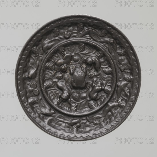 Mirror, Chinese art, Chinese culture, Tang 618–907, bronze mirror with beasts fantastical, frogs, birds, vines, 8th century Tang Dynasty, China, mirror, height 0.9 cm, diameter 9.8 cm, A circular dark brown object with a raised rim sits against a light gray background; the surface shows a densely textured central medallion and surrounding band with sculpted, rounded organic forms and flowing, curled shapes that resemble clusters and stylized foliage, all rendered in the same dark brown color with subtle highlights and lowlights emphasizing the relief.
