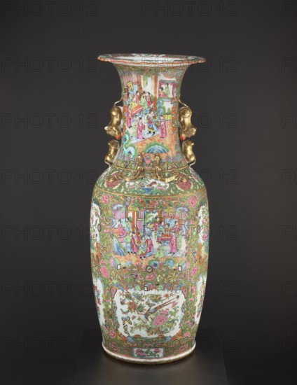 Vase, Chinese, 19th century, colored porcelain vessel with figurative court scenes, butterflies, plant and floral ornamentation; height 93.0 cm, diameter 34.0 cm., A tall decorative porcelain vase stands against a dark background, featuring ornate painted scenes and floral motifs in a palette of pink, green, gold, red, blue, white, and touches of black. The vase has a flared rim and a long neck with painted narrative panels showing groups of people in colorful robes, and the body displays framed panels with birds and floral arrangements surrounded by dense scrolling foliage and blossoms. Gilded sculptural handles shaped like stylized animal heads are attached at the neck, and additional raised gold ornamental elements accent the shoulder area. The lower section repeats floral garlands and intricate decorative borders, and the overall surface is richly detailed with many small motifs and repeated patterns.