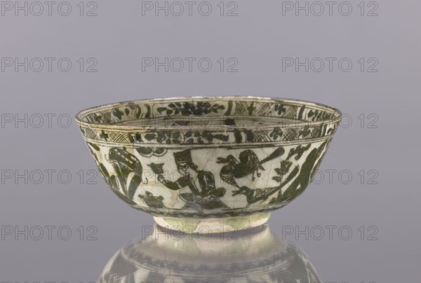 Bowl, Abdullazad Mirza Baba fl. ante 1939, Islamic art, Persian art, Persian culture, Qajar dynasty 1785–1925, ceramics, tableware, utility ceramics, bowls, female figures, figural scenes, rim decoration: figures, gazelle, falcons, architecture, late, 2nd half of the 19th century, Iran, vessel, height 8.5 cm, diameter 20 cm, A shallow ceramic bowl with a rounded foot displayed against a pale gray background, decorated with dark green painted figures and stylized foliage on a white base, showing a seated human figure wearing a tall hat and holding an object, accompanied by bird-like creatures and leafy motifs around the exterior, with a narrow decorative band near the rim and visible hairline craquelure and areas of glaze wear; colors visible include white, dark green, pale yellowish-green, and gray.