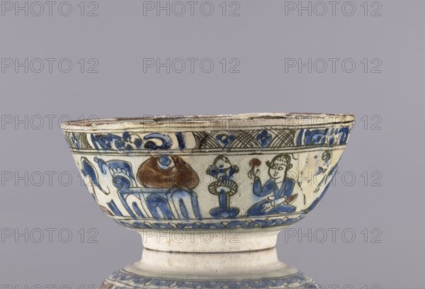 Bowl, Abdullazad Mirza Baba fl. ante 1939; Islamic art, Persian; Qajar dynasty 1785–1925; figurative scenes, female figures, dragons; ceramics; household tableware; glazed ceramic bowl; decoration on rim: architecture resembling a ziggurat, demons, figures, horse, palmettes; 2nd half of the 19th century; Iran; vessel; height 8 cm, diameter 19 cm, A ceramic bowl with a flared rim and a short pedestal base sits against a muted gray background; the bowl's surface is off-white with painted decoration in blue, brown, green, and black, including a band of floral and geometric motifs near the rim and a frieze below showing a seated humanlike figure in blue holding a small round object, a stylized plant or vase motif, and abstract organic shapes; the rim shows signs of wear and small chips, and the glaze has a slightly crackled appearance.