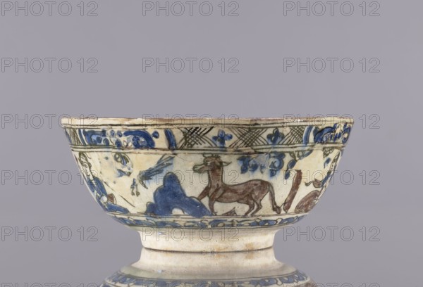 Bowl, Abdullazad Mirza Baba fl. ante 1939; Islamic art, Persian; Qajar dynasty 1785–1925; 2nd half of the 19th century; Iran. Glazed ceramic household tableware vessel bowl. Height 8 cm, diameter 19 cm. Decoration: figurative scenes with female images, dragons, demons, figures, a horse, palmettes; rims decorated with architecture resembling a ziggurat., A shallow ceramic bowl on a short foot with painted decorative scenes around its exterior showing a reclining animal figure, a standing animal, floral and foliate motifs, and a human figure, all rendered in brushwork; visible colors include blue, brown, green, cream, and hints of black against a pale background, with areas of glazing and slight wear.