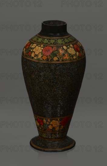Vase, Qajar dynasty 1785–1925, Persian, Islamic art; lacquer vase, 19th century, Iran; vessel, height 32.0 cm, diameter 17.0 cm. Decoration: densely placed plant motifs peonies with gold contouring; on the collar and above the foot flowers red and gold. Inside a card no. 54 with an inscription in Italian noting it is a lacquer vase., The image shows a tall ceramic vase with a narrow neck and flared base, decorated with floral bands and patterns. The upper rim and neck are dark, almost black, while a band near the shoulder features painted flowers in red, yellow, orange, and green against a darker background. The main body has a dark, textured surface with subtle floral motifs in deep blue and muted green tones with small highlights of yellow. A lower band near the base repeats the colorful floral motif with reds, yellows, oranges, and greens, and the base itself is dark with decorative patterns and a thin lighter edge. The overall color palette includes black, dark blue, green, red, ye...