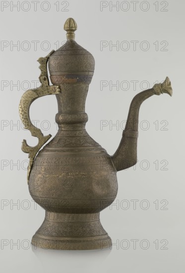 Jug aftabe, aftabe, geometric and plant ornament, dragons, zoomorphism; Decoration: dense plant and geometric ornament. Persian, Qajar dynasty 1785–1925, 19th century; Central Asia, / Iran ; vessel; height 34.0 cm, width 22.7 cm, diameter 13.3 cm., An ornate metal ewer with a bulbous body, a flared pedestal base, a tall neck topped by a domed lid with a finial, a curved spout with a floral-shaped tip, and a decorative handle attached to the side; the surface is covered in intricate engraved patterns and textured motifs. The visible colors are brown and brass tones with hints of darker patina and subtle greenish aging.
