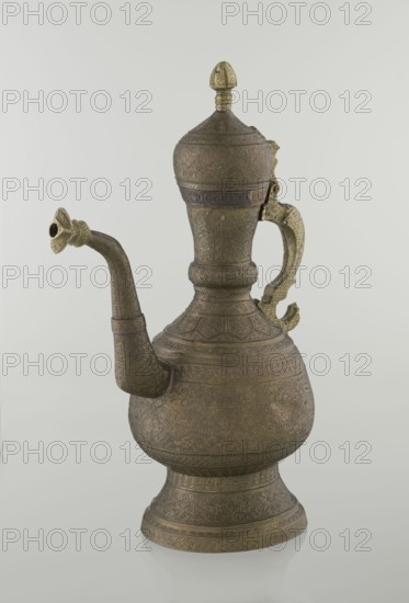 Jug aftabe, gift, repossession, Islamic art, Persian culture, Qajar dynasty 1785–1925, aftabe, geometric ornament, plant ornament, dragons, zoomorphism, Decoration: dense plant and geometric ornament, 19th century, Central Asia, Iran, vessel, height 34.0 cm, width 22.7 cm, diameter 13.3 cm, A metal ewer with an ornate rounded base, a bulbous body, a tall narrowed neck, a domed lid topped by a finial, a curved spout with a flared decorative tip, and a shaped handle; the surface is covered in intricate engraved patterns and embossed designs. The object appears in shades of bronze, brass, and muted gold against a pale, light gray background.