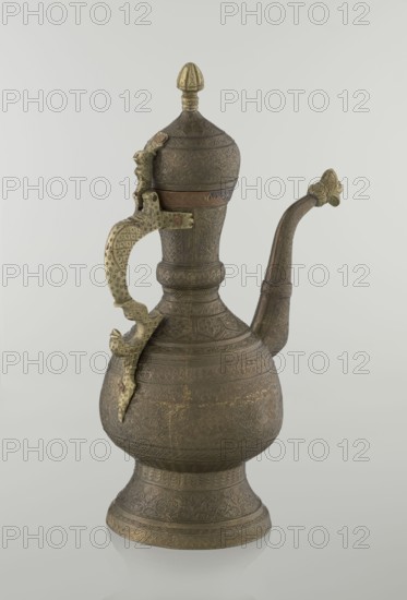 Jug aftabe, Persian, Qajar dynasty 1785–1925, 19th century. Materials/technique: vessel aftabe with dense plant and geometric ornamentation, featuring geometric patterns, plant motifs, dragons and zoomorphic decoration. Dimensions: height 34.0 cm, width 22.7 cm, diameter 13.3 cm. Place of origin: Iran possibly Central Asia., A metal vessel with a rounded base and a tall neck topped by a domed lid, featuring ornate engraved patterns all over its surface; the vessel has a curved spout extending outward and upward from the neck and a decorative handle with sculpted elements attached to the side; the metal shows shades of brown and brass with areas of darker patina and some lighter golden highlights; the background is a plain light gray.