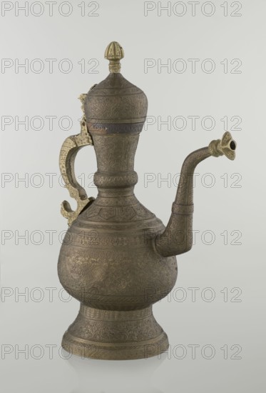 Jug aftabe, aftabe, geometric and plant ornament, dragons, zoomorphism; dense plant and geometric decoration; Persian, Qajar dynasty 1785–1925, 19th century; Central Asia, / Iran ; vessel, height 34.0 cm, width 22.7 cm, diameter 13.3 cm., An ornate metal ewer with a bulbous body, a flared foot, a long curved spout, a tall neck with a domed lid topped by a finial, and a hinged decorative handle; the surface is covered in dense engraved patterns and textured motifs, and the handle and finial show a brighter metallic tone while the main body and spout appear darker with a patinated finish in shades of bronze, gold, and brown against a pale gray background.