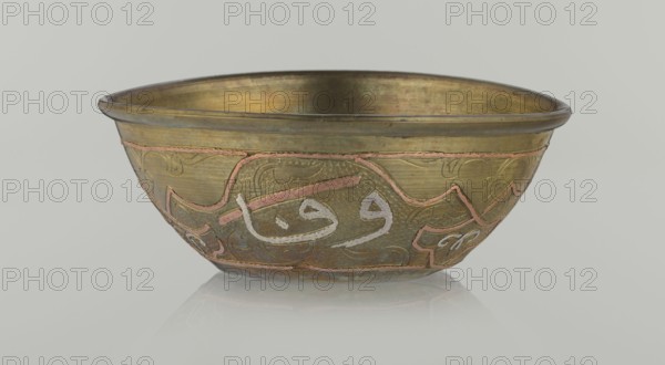 Bowl, Islamic art, Arabic culture, arabesque ornament, calligraphy, Arabic inscriptions, geometric motifs, 19th century, Middle East, possibly Syria, vessel, height 4.9 cm, diameter 13.3 cm, A metal bowl with a wide rim and rounded sides sits on a reflective surface, showing colors of brassy gold, muted greenish-gold, pinkish copper inlaid lines, and silvery-white accents; the exterior features a textured surface with swirling decorative patterns and curving inlaid bands, while the interior appears smoother with a similar brassy-gold tone; the rim is slightly darker and the bowl casts a soft reflection below.