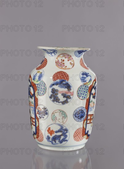 Vase, Tashiro maker/trading company, Japanese, colored porcelain, ceramics, Meiji period 1868–1912, 2nd half of 19th century. Hizen, Arita, Japan. Height 28.5 cm; diameter 19.0 cm. Decoration: figurative scenes with landscape background, peonies, camellias, wisteria, fish, pine trees, asanoha pattern. Provenance unknown., A white ceramic vase decorated with a pattern of round medallions and vertical panel shapes, featuring painted scenes and motifs in blue, red, green, pink, and gold tones, with a flared rim and a gently tapered body standing on a short base, set against a plain gray background.
