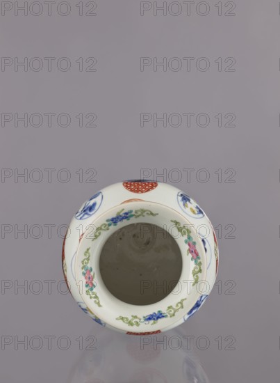 Vase by Tashiro, Japanese, colored porcelain, ceramics; Meiji period 1868–1912, 2nd half of 19th century. Hizen Arita, Japan. Height 28.5 cm, diameter 19.0 cm. Decoration: figurative scenes with landscape background, peonies, camellias, wisteria, fish, pine trees, asanoha pattern; genre scenes. Provenance unknown., A white ceramic vessel viewed from above with a round open mouth, decorated around the rim with a floral garland in green, pink, blue, and teal, and additional circular motifs in red and blue on the outer surface; the interior appears plain and light grayish, and the background is a muted lavender-gray.