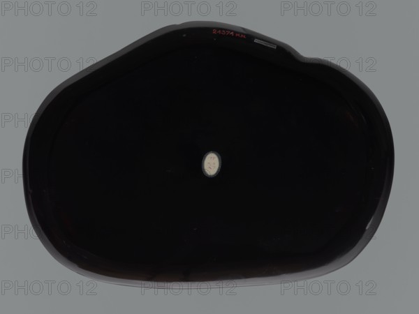 Tray, lacquer, monkeys, sambiki-no saru, Japanese art, trays, Japanese culture, Meiji 1868–1912, Tray in the shape of an irregular oval. Brown, black, and red lacquer decorated using the chôshitsu technique, unsigned, early 20th century Meiji period, Japan, vessel; height 2.5 cm, width 27.0 cm, depth 37.0 cm, A large dark oval object with a glossy surface sits against a flat gray background; the object appears almost black with subtle reflections and highlights in dark brown and deep purple along its rounded edges, and a small pale oval area with a light beige tone is visible near the center.