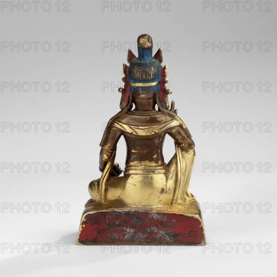 Jambhala, unknown sculptor; deities of wealth iconography; Himalayan/Tibetan Buddhist art; Yellow Jambhala Tib. dzam b+hA lha — deity of wealth. Shown seated, holding a bijapuraka citrus fruit in his right hand and a mongoose in his left. 18th century, Tibet; sculpture; height 7.7 cm, width 4.7 cm, depth 3.2 cm., A small statue viewed from the back showing a seated figure on a rectangular base, with visible colors including gold, blue, red, brown, and a few darker gray areas; the figure has a rounded headdress with blue and red accents, a topknot, and ornamental flanges at the sides, a smooth back and shoulders draped with a robe that appears gold, arms resting at the sides with detailed cuffs, and the rectangular base shows worn red paint with mottled darker patches.