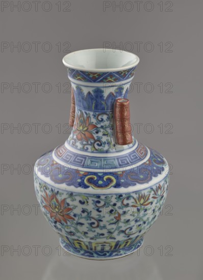 Vase with threads in the shape of bamboo twigs; maker, Chinese; Qing dynasty 1644–1911, Qianlong period 1736–1795; colored porcelain; plant motifs including lotus tendril ornament and artemisia leaves; decoration: lotus tendril on the belly, lambrequin ornament on the shoulders, geometric and plant borders on the neck; vessel; height 20 cm, diameter 14.5 cm, weight 0.8 kg., A ceramic vase with a flared rim and bulbous body sits against a neutral gray background; the vase is primarily white with decorative bands and floral patterns in blue, red, green, yellow, and touches of brown, featuring swirling blue motifs and stylized flower designs, a few vertical applied handles in a reddish-brown color with gold-like accents, and several geometric border patterns in blue and green wrapping around the neck and shoulder.
