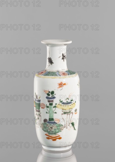 Vase, gift, Paderewski, Ignacy Jan 1860–1941, Chinese, Qing dynasty 1644–1911, 19th century; colored porcelain with baigu hundred antiquities ornament; vase; height 20.8 cm, diameter 7.5 cm., A slender cylindrical porcelain vase with a flared rim, predominantly white with painted decorative motifs; the neck shows a few small black leaf-like marks, a circular band near the shoulder features green crosshatch panels and round floral medallions in pink and green, and the body displays a few stylized ornamental objects and floral forms in green, yellow, orange, blue, and black, with delicate outlines and small decorative accents in those colors; the vase sits on a subtle white base against a plain gray background.