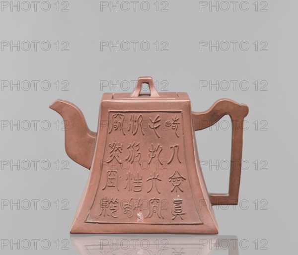 Teapot with a lid, tea, Harbin China, ceramics, Chinese art, Chinese culture, Qing 1644–1911, Yixing style, inscriptions, red-brown stoneware, 19th century, China, vessel; height 12.2 cm, width 16.3 cm, A reddish-brown teapot with a trapezoidal body and a flat top, featuring a short triangular lid handle, a curved spout on the left, and a rectangular handle on the right; the front and sides show recessed panels with incised decorative markings, and the object sits on a reflective surface against a pale gray background with visible colors including reddish-brown and gray.