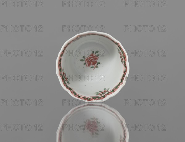 Bowl, ceramic vessel with colorful decorations in Kangxi style, decorated with floral motifs, plum trees and bird images; Qing dynasty Kangxi period, 1662–1722; China; height 5.4 cm, diameter 8.8 cm., A white ceramic bowl with scalloped edges sits against a gray background, showing painted floral decorations in red and green on the inside and along the rim, with a pale reflection beneath that mirrors the bowl and its floral motif; colors visible include white, gray, red, and green.