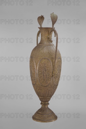 Vase, 19th century, India; vessel, height 65.0 cm, width 27.5 cm, weight 2.95 kg. On the belly six ovoid reserves with figural decoration: four female figures with wreaths and two images of Vishnu. Surface decorated overall with plant and animal motifs, cobras snakes, fish, geometric and plant ornament, figural scenes, halos, maces, processions, flutes, clubs; religion Vishnu., An ornate tall vase with a rounded body and a flared neck resting on a stepped pedestal base, rendered in shades of brown and muted gold; the surface is richly embossed with repeating floral and foliate patterns and several oval medallions each containing a raised human figure in relief; two long, curved handles extend from the neck to the shoulder and terminate near the body, and two decorative leaf-shaped finials rise above the rim; the background is a neutral gray.