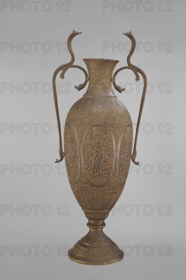 Vase, repossession Kraków - Vishnu, Indian art, Indian culture, cobras snakes, plant ornament, geometric ornament, figural scenes, fish, halos, maces, religion, snakes, processions, flutes, clubs. On the belly six ovoid reserves with figural decoration four female figures with wreaths, two images of Vishnu; plant and animal motifs on the entire surface. 19th century, India, vessel; height 65.0 cm, width 27.5 cm, weight 2.95 kg., A tall decorative vase with an elongated ovoid body and a flared scalloped rim sits against a neutral gray background; the vase is predominantly brown with subtle greenish accents and shows ornate low-relief surface decoration of repeating floral and foliate patterns and framed oval medallions containing raised human figures; two long sinuous handles rise from the shoulders and curve outward and upward, each terminating in a stylized animal head, and a pair of short decorative projections connect the handles to the neck; the vessel stands on a stepped rounded f...