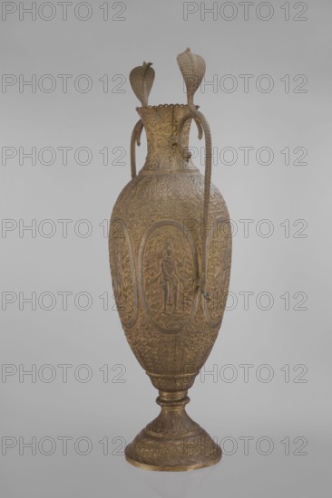 Vase, repossession Kraków - Vishnu; Indian art; Indian culture; cobras snakes; plant ornament; geometric ornament; figural scenes; fish; halos; maces; religion; snakes; processions; flutes; clubs. On the belly six ovoid reserves with figural decoration four female figures with wreaths, two images of Vishnu; plant and animal motifs on the entire surface. 19th century, India. Vessel. Height 65.0 cm; width 27.5 cm; weight 2.95 kg., An ornate tall vase with a rounded body and a flared scalloped rim, shown standing on a pedestal base; the surface is richly textured with raised decorative patterns including oval medallions containing human figures in relief, scrolling foliage, and repeated floral motifs; two long, curved handles rise from the shoulder and attach near the rim, each terminating in a stylized serpent or leaf-like form; the overall color is a metallic golden bronze with subtle darker patina in recessed areas and hints of muted green in a small spot where the surface shows slight...