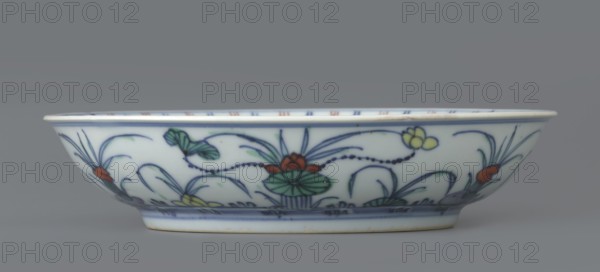 Plate, gift, Paderewski, Ignacy Jan 1860-1941, Chinese art, Chinese culture, Qing 1644–1911, Qing style, ceramics, colored porcelain, lotuses, ducks, decoration in mirror and outside, 1st half of the 18th century, China, vessel, height 3.5 cm, diameter 15.8 cm, A shallow oval ceramic bowl with a smooth white surface decorated with floral and botanical motifs in blue, green, red, yellow, and a hint of black outlining; the rim is slightly flared and shows a thin blue band, the sides feature painted leaves, stylized flowers, and curving stems, and the base has concentric blue lines and a subtle beige foot rim, all set against a neutral gray background.