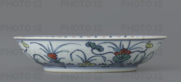 Plate, Paderewski, Ignacy Jan 1860-1941, Chinese art, Chinese culture, Qing 1644–1911, Qing style, ceramics, colored porcelain, lotuses, ducks, decoration in mirror and outside, 1st half of the 18th century, China, vessel, height 3.5 cm, diameter 15.8 cm, A shallow round ceramic bowl with a white base color decorated around the exterior with a painted floral and foliage pattern in blue, green, red, yellow, and a bit of purple, featuring stylized leaves, stems, and flower motifs outlined in blue; the rim has a thin blue line and the foot rim shows a faint bluish band and a pale warm edge, all set against a neutral gray background.