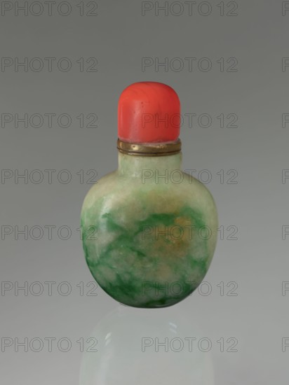 Snuffbox with spoon, Chinese, Qing dynasty 1644–1911, 19th century; moon bottle form; vessel; height 7.5 cm, width 4.5 cm, depth 2.8 cm., A small rounded bottle with a smooth, mottled body showing shades of green and pale cream with a few darker green swirls and a hint of muted yellow, topped by a bright red rounded cap set into a thin metallic band that has a brass tone, all shown against a uniform gray background with a faint reflection of the bottle visible below.