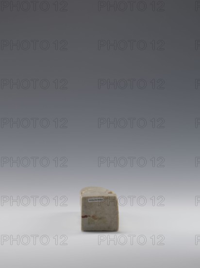 Sage, gift; figurine; men; Chinese art; Chinese culture; Qing 1644–1911, 19th century; China; sculpture; height 16.8 cm, width 4.6 cm, depth 4.3 cm., A small rectangular block with rounded top edges sits centered on a smooth surface, showing a worn, slightly mottled appearance in beige and tan with faint patches of reddish and brown discoloration; the background transitions from light gray near the surface to darker gray toward the top.