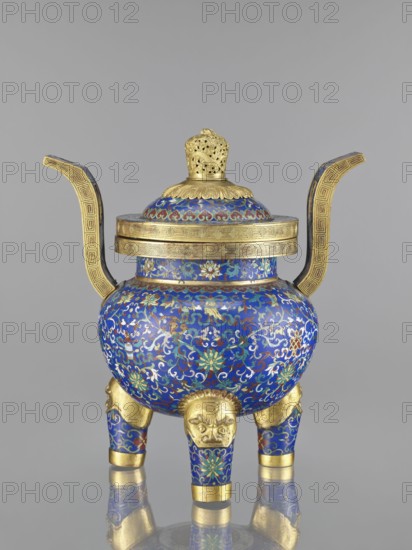 Ding-type incense burner with cover, cloisonné enamel, Qing dynasty 1644–1911, 19th century, China; decorated with bats, dragons, leiwen and meander ornament, plant motifs; vessel; height 38.5 cm, width 34.5 cm., An ornate vessel with a domed lid and two upward-curving handles sits on a reflective surface, decorated primarily in rich blue with intricate swirling floral and vine patterns in green, white, red, and gold; the lid and rim feature gold bands with geometric motifs and a pierced gold finial, while the body rests on three short legs covered in the same blue and floral enamel, each leg topped by a gold lion-like mask and finished with gold bands at the feet.