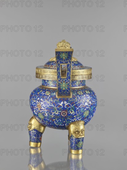 Ding-type incense burner with cover, cloisonné enamel, Qing dynasty 1644–1911, 19th century, China; decorated with bats, dragons, leiwen and meander ornament, plant motifs; vessel; height 38.5 cm, width 34.5 cm., A round lidded vessel standing on a group of three short legs shaped with stylized animal heads, featuring a dominant blue background with intricate floral and scrolling patterns in gold, green, red, and white, with gold-colored rims, accents, and sculpted details including a decorative finial on the lid and a vertical handle-like element rising from the top, all set against a plain neutral gray backdrop.