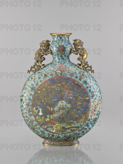 Vase — moon bottle pilgrim with a sleeve, maker, cloisonné enamel; Qing dynasty 1644–1911, 19th century, China; decorated with peacocks, herons, dragons, flower tendril and lotus tendril ornament iconography; height 39.3 cm, width 28.5 cm, depth 11.4 cm., A round, flattened vase with a narrow neck and flared rim sits against a neutral background, decorated overall in a turquoise blue ground with ornate swirling cloudlike patterns in darker blue and gold; a large circular panel on the body shows an intricate scene with a peacocklike bird and stylized floral and landscape motifs rendered in deep blue, green, red, gold, and touches of white; two sculpted handles in a metallic gold tone shaped like stylized mythical creatures flank the neck and extend onto the shoulder; the rim, base edge, and some raised decorative elements show a warm metallic gold color, and the surface has areas of subtle patina and wear that create variations in color and texture.