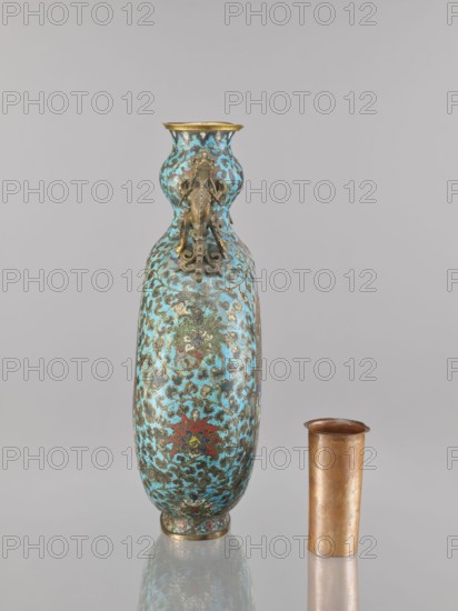 Vase — moon bottle pilgrim with a sleeve; maker, ; cloisonné enamel; Qing dynasty 1644–1911, 19th century; China; motifs: peacocks, moon bottles, herons, dragons, flower tendril, lotus tendril; Chinese art/culture; vessel; height 39.3 cm, width 28.5 cm, depth 11.4 cm., A tall, slender vase with a bulbous neck and narrow mouth stands next to a shorter cylindrical cup; the vase is predominantly turquoise with patterns in darker teal, brown, gold, and touches of red, and it has gold-colored ornamental mounts and fittings including a decorative relief element on the neck, while the cup is metallic with a warm coppery-brown tone.