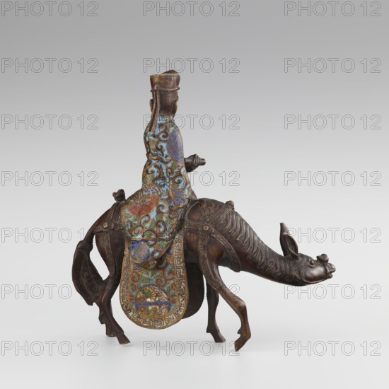 Sage on a Mule, cloisonné enamel, Qing 1644–1911, 19th century, China; sculpture depicting a sage riding a mule with men/figurines, mules, birds and zoomorphic motifs, plant motifs, meander ornament and scrolls; height 26.0 cm, width 25.5 cm, depth 6.0 cm., A bronze figurine of a person seated on an animal, the person wearing a long, flowing garment with intricate swirling patterns in blue, turquoise, green, red, and gold, and a tall headdress in bronze tones; the animal has a long neck and elongated head with pronounced ears and snout, rendered in dark brown bronze with visible sculpted muscles and ridges, and a decorative saddle cloth hanging down with ornate multicolored patterns echoing the garment’s colors and gold detailing; the overall color palette includes dark brown, bronze, blue, turquoise, green, red, and gold, set against a neutral light gray background.