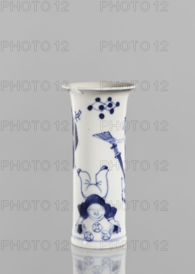 Flute-type vase, figurative scenes, ceramics, blue-and-white porcelain, Chinese, musicians, stars; 17th century Kangxi period, 1662–1722, Qing dynasty, China; vessel; height 12 cm, diameter 5.6 cm., A tall cylindrical porcelain vessel with a flared rim, predominantly white with blue painted decorations; the surface shows a painted scene including a small smiling figure wearing a rounded hat near the base, stylized motifs and a few abstract dot-and-line designs near the top, and other slender decorative elements extending along the body. The colors visible are white and dark blue, with soft gray reflected tones on the surface and a neutral light gray background.